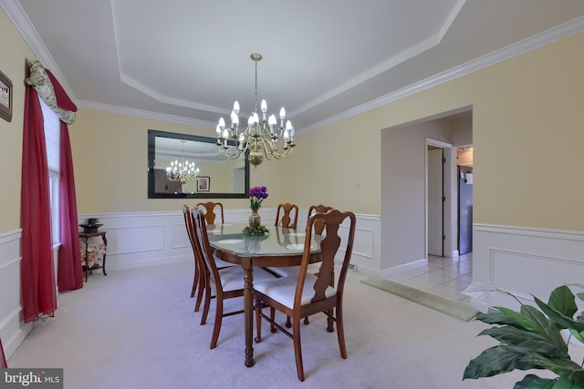 carpeted dining room with ornamental molding, a chandelier, and a raised ceiling