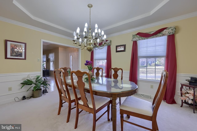 carpeted dining space featuring crown molding, a chandelier, and a raised ceiling