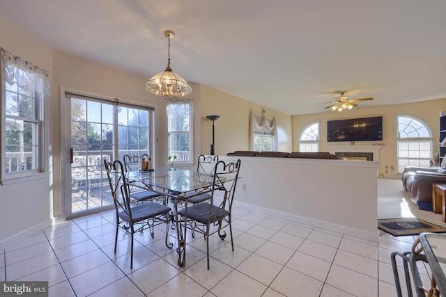 dining space with ceiling fan with notable chandelier, a healthy amount of sunlight, and light tile patterned floors