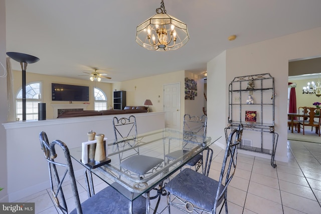 tiled dining space featuring ceiling fan with notable chandelier