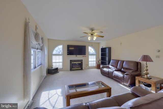 living room with a high end fireplace, a healthy amount of sunlight, carpet, and ceiling fan