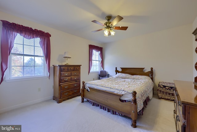 carpeted bedroom featuring multiple windows and ceiling fan