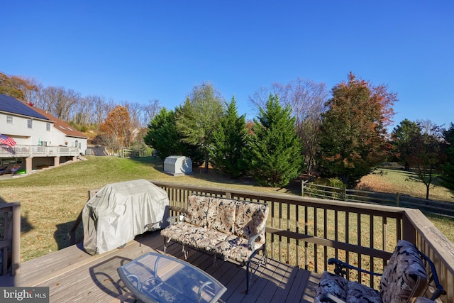 deck with grilling area, a shed, and a lawn