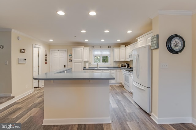 kitchen with light hardwood / wood-style flooring, white cabinetry, crown molding, and white appliances