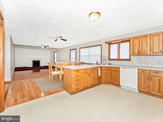 kitchen with kitchen peninsula, ceiling fan, light wood-type flooring, dishwasher, and sink