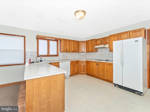 kitchen featuring white appliances, sink, and kitchen peninsula