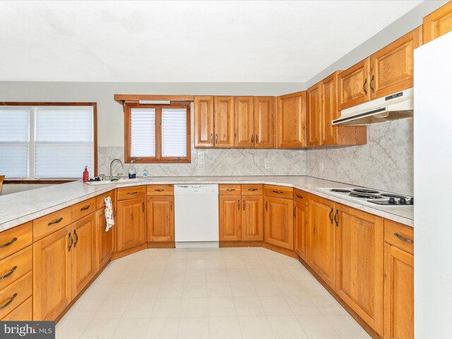 kitchen featuring white appliances, backsplash, and sink