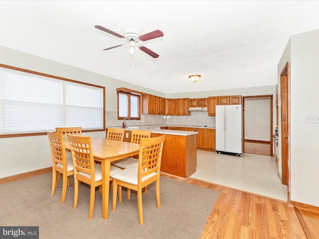 dining space with light hardwood / wood-style flooring, sink, and ceiling fan