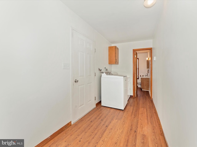 laundry area featuring light hardwood / wood-style floors, washer / clothes dryer, and cabinets