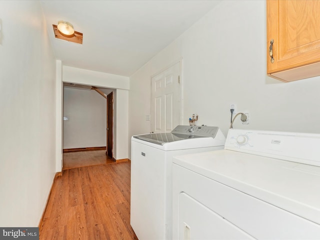 laundry room with washing machine and dryer, cabinets, and light wood-type flooring