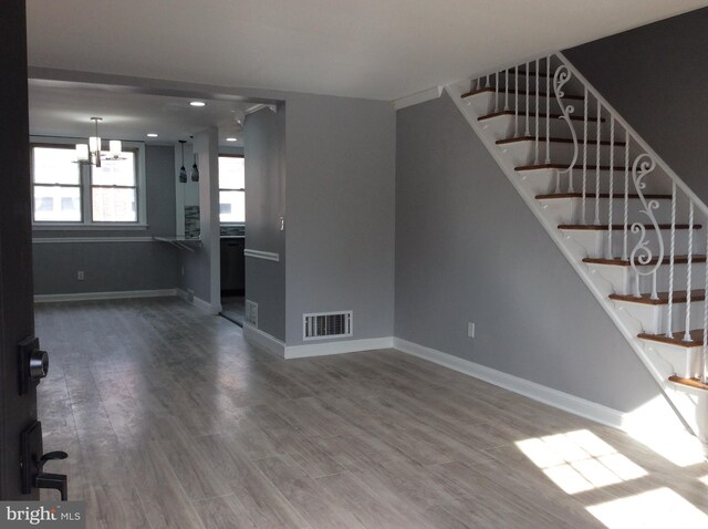 unfurnished living room featuring a chandelier and wood-type flooring