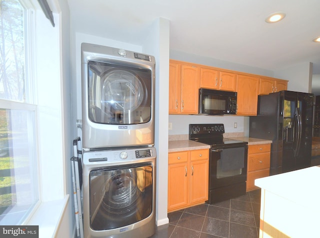 laundry room with stacked washer / dryer and dark tile patterned floors