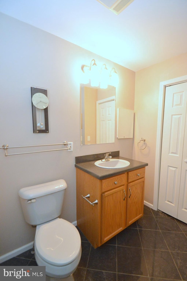 bathroom with toilet, vanity, and tile patterned floors