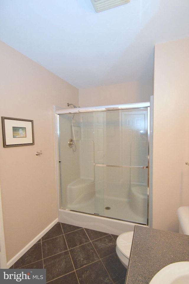 bathroom with a shower with shower door, tile patterned floors, and toilet