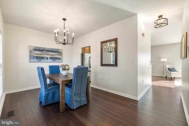 dining area featuring dark hardwood / wood-style floors and an inviting chandelier