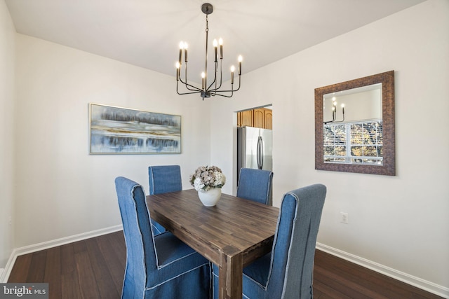 dining area with dark wood-type flooring and an inviting chandelier