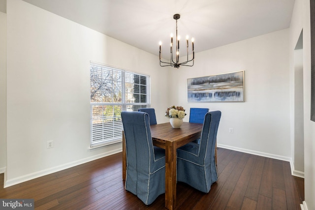 dining area featuring dark wood-type flooring and an inviting chandelier