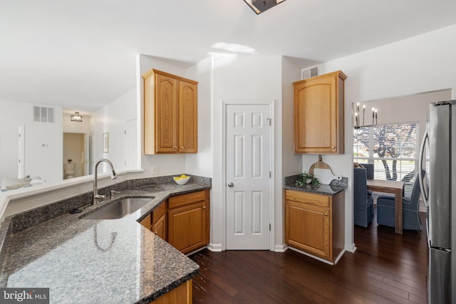 kitchen featuring dark stone counters, stainless steel fridge, sink, and dark hardwood / wood-style flooring