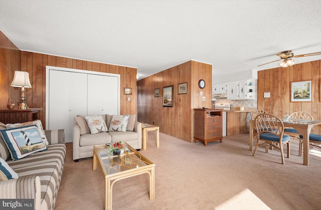 carpeted living room with wooden walls, a textured ceiling, and ceiling fan