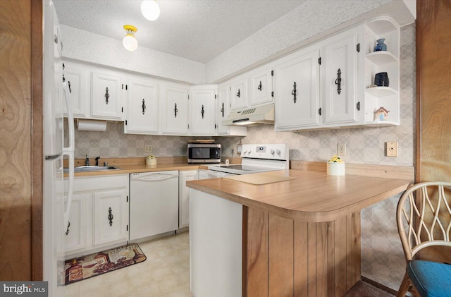 kitchen with white appliances, a textured ceiling, kitchen peninsula, white cabinetry, and custom range hood