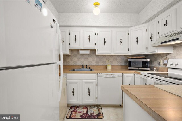 kitchen featuring custom exhaust hood, a textured ceiling, white cabinetry, sink, and white appliances