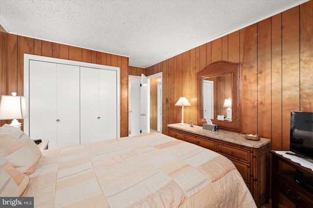 bedroom with a closet, a textured ceiling, and wooden walls