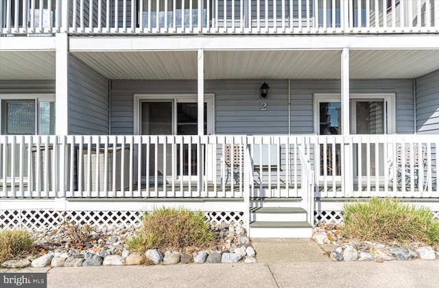 view of exterior entry with a balcony and covered porch