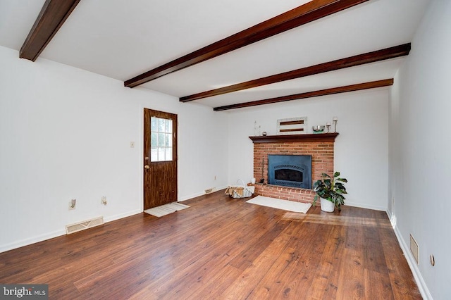 unfurnished living room with hardwood / wood-style floors, beam ceiling, and a brick fireplace