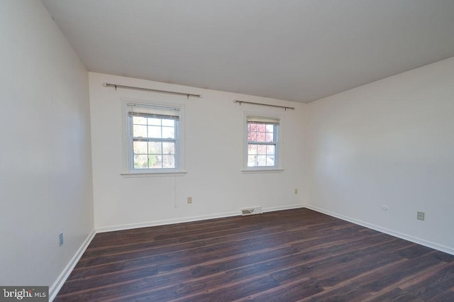 empty room featuring dark hardwood / wood-style flooring and a healthy amount of sunlight