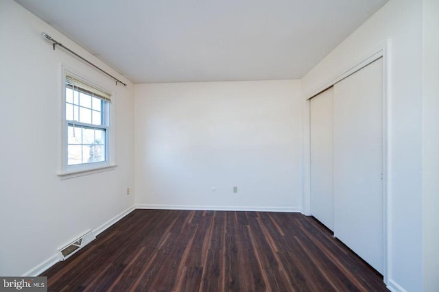 unfurnished bedroom with dark hardwood / wood-style flooring and a closet