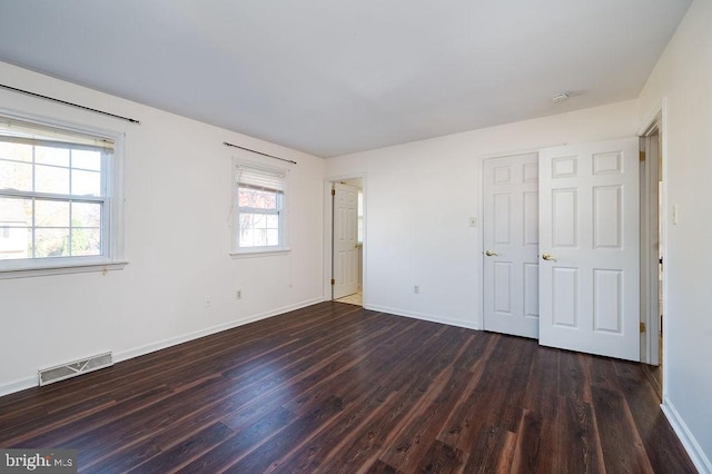 unfurnished bedroom with dark wood-type flooring and multiple windows