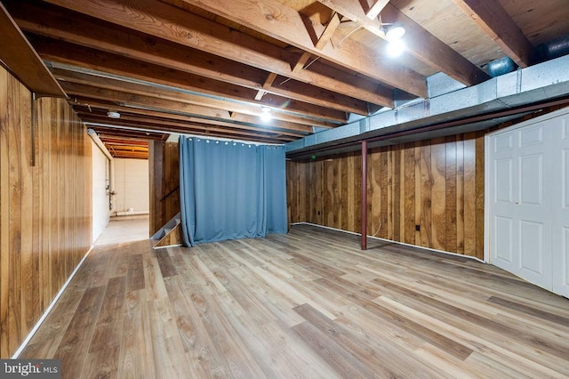 basement featuring wooden walls and light wood-type flooring