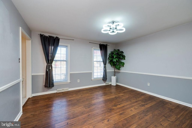 spare room featuring hardwood / wood-style floors and a chandelier