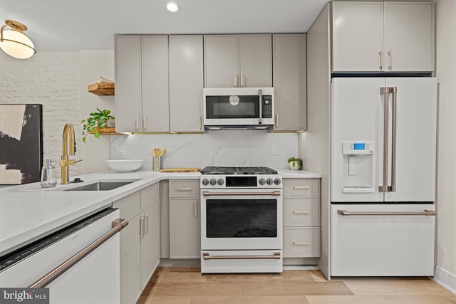 kitchen featuring light hardwood / wood-style flooring, sink, light stone counters, and white appliances