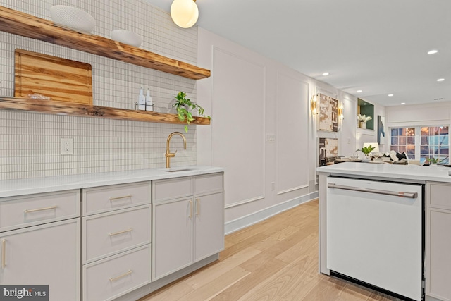 kitchen featuring white cabinets, tasteful backsplash, white dishwasher, light hardwood / wood-style flooring, and sink