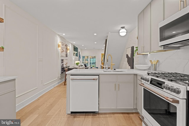 kitchen featuring sink, white cabinets, light wood-type flooring, and white appliances