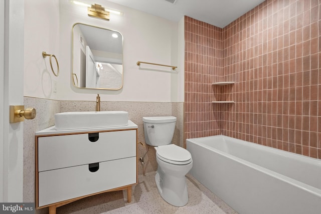 full bathroom featuring vanity, tile walls, tiled shower / bath combo, and toilet