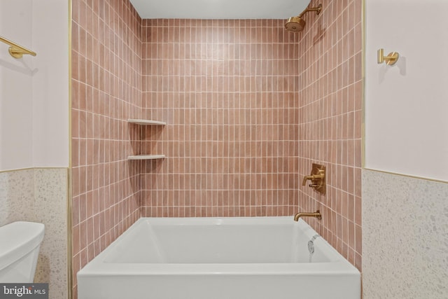 bathroom featuring tile walls, tiled shower / bath combo, and toilet