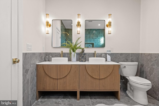 bathroom featuring vanity, toilet, and tile walls