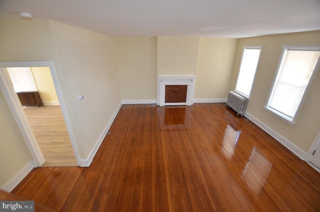 unfurnished living room with radiator and hardwood / wood-style flooring