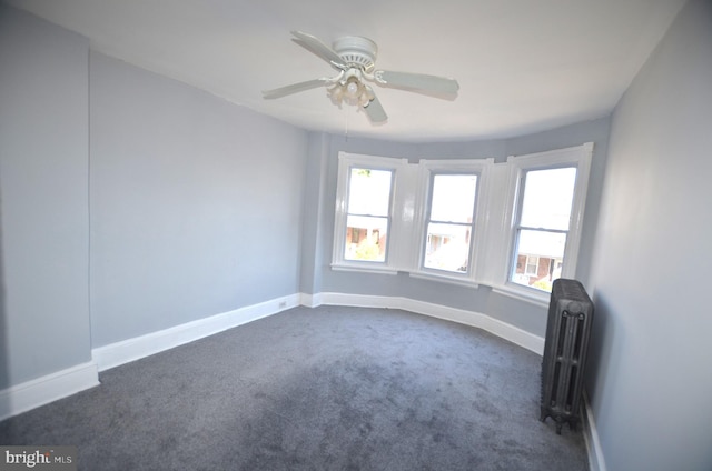 spare room featuring ceiling fan, radiator heating unit, and dark carpet