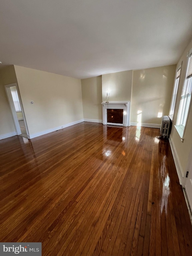 unfurnished living room featuring heating unit and dark hardwood / wood-style floors