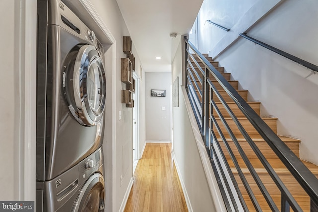 laundry area with light hardwood / wood-style floors and stacked washing maching and dryer