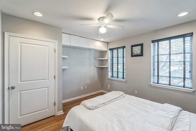 bedroom with multiple windows, hardwood / wood-style flooring, and ceiling fan