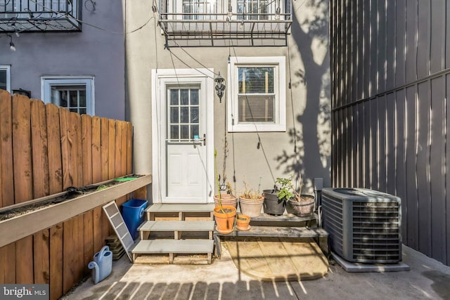 view of exterior entry featuring a patio area, central AC, and a balcony