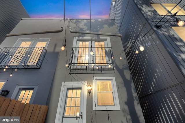 back house at dusk featuring a balcony