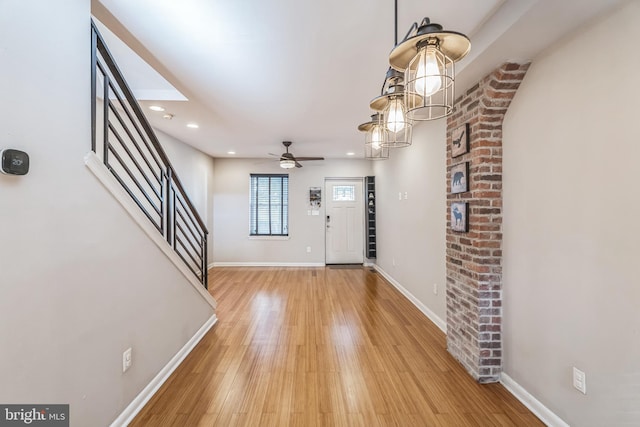 entrance foyer with hardwood / wood-style floors and ceiling fan with notable chandelier