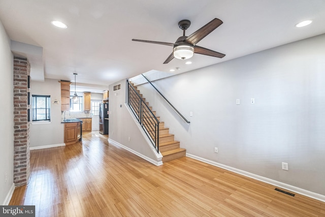 unfurnished living room featuring sink, light hardwood / wood-style floors, and ceiling fan