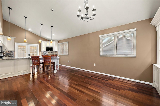 dining space with dark hardwood / wood-style floors, high vaulted ceiling, and an inviting chandelier