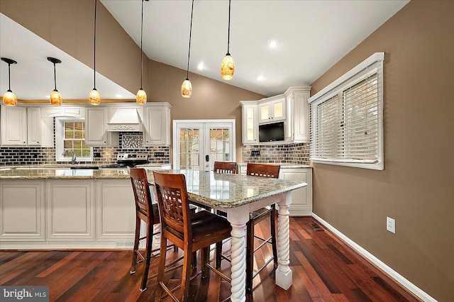 kitchen featuring white cabinets, light stone counters, hanging light fixtures, and stainless steel range oven